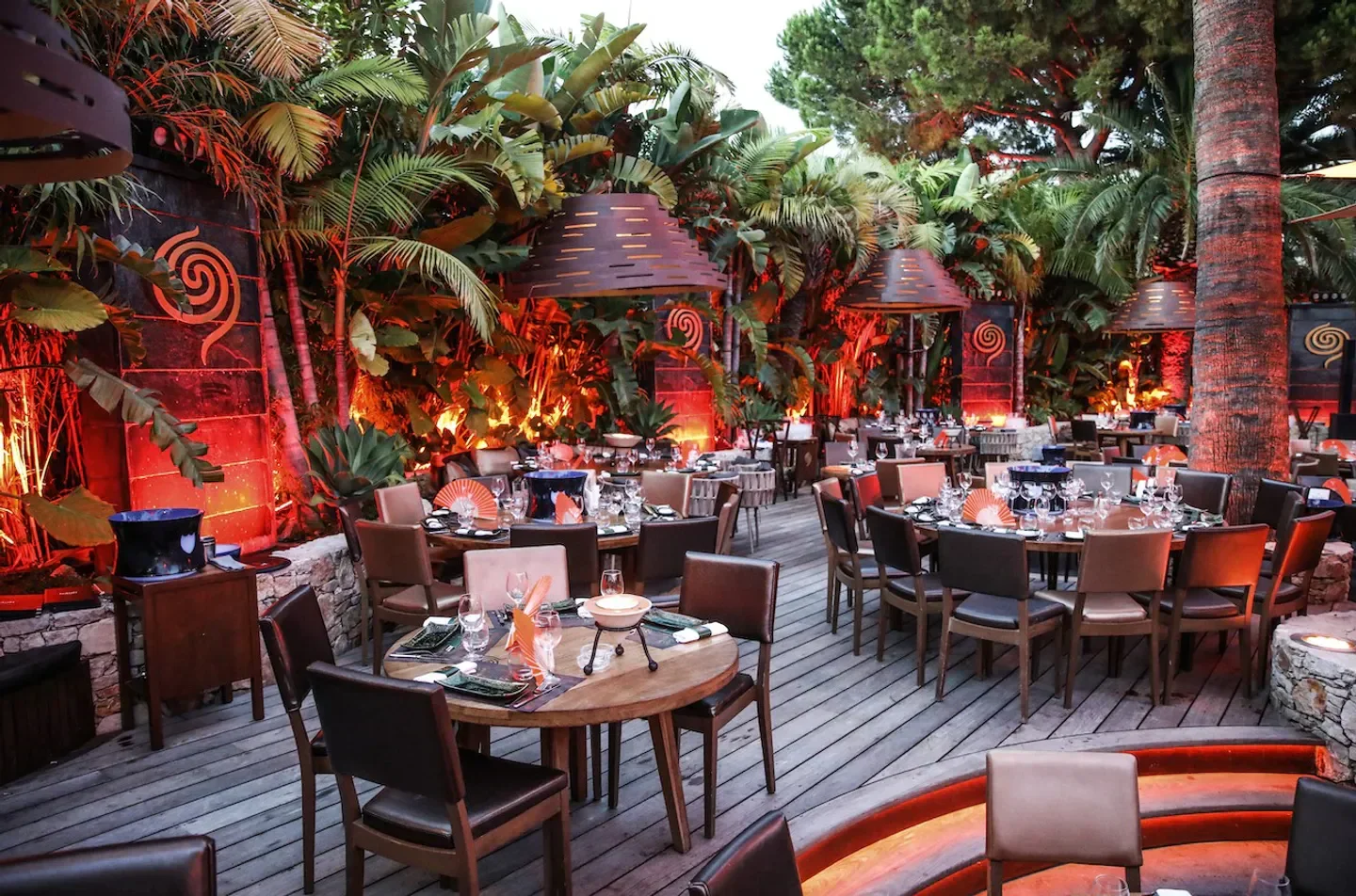 Outdoor dining at Baoli Cannes, lush greenery and warm lighting create a luxurious ambiance.