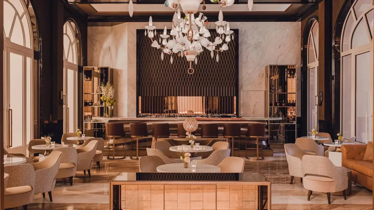 Interior of Carlton Restaurant in Cannes, featuring bar, seating and an elaborate chandelier.