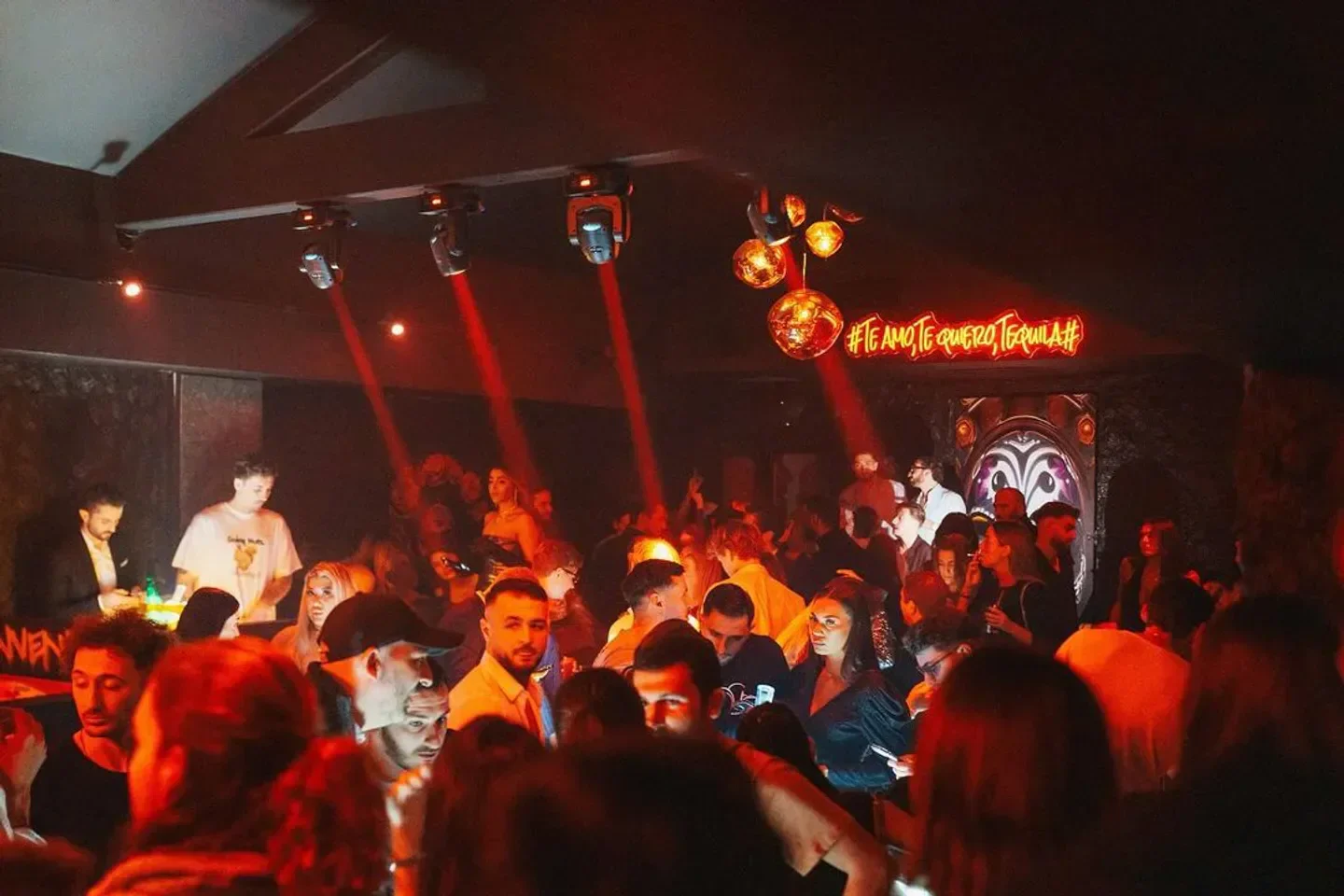 Inside Elva nightclub in Cannes, with a crowd of people partying under red lights.