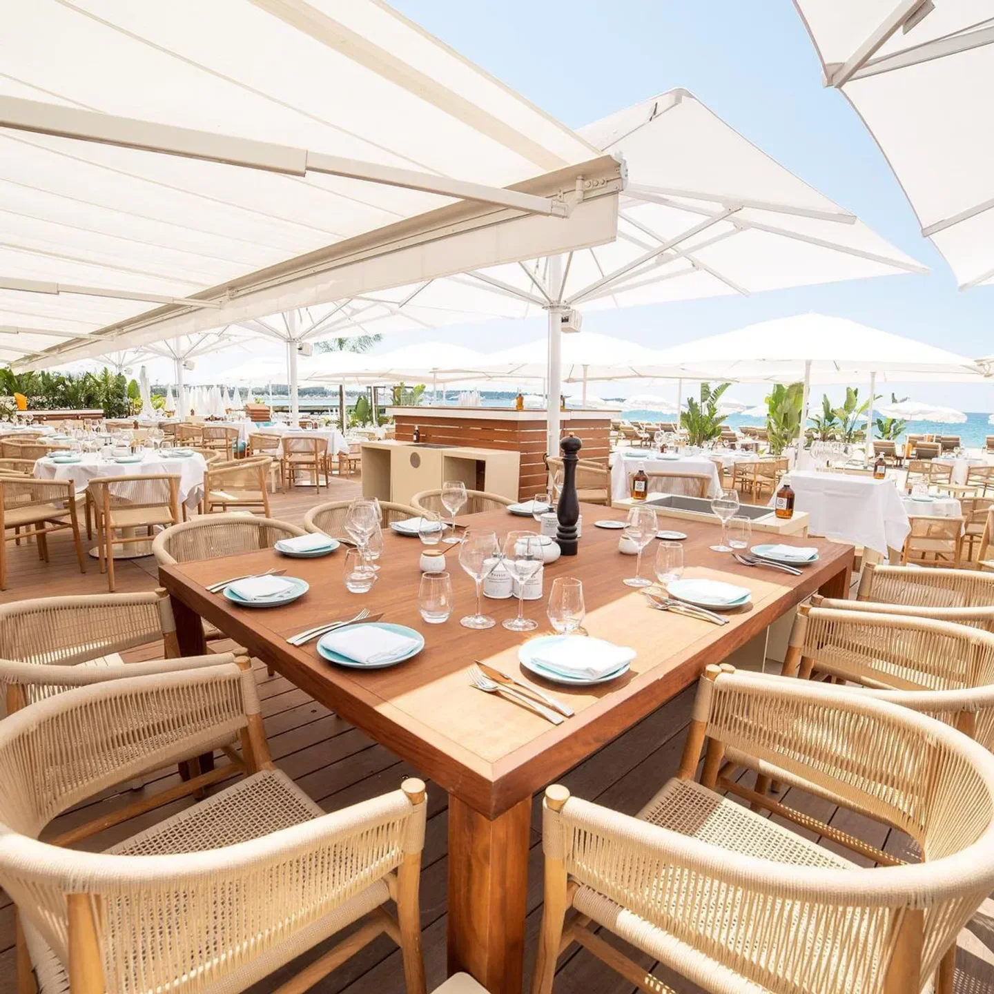 Dining area at La Mome Plage beach club in Cannes, with ocean views and stylish decor.