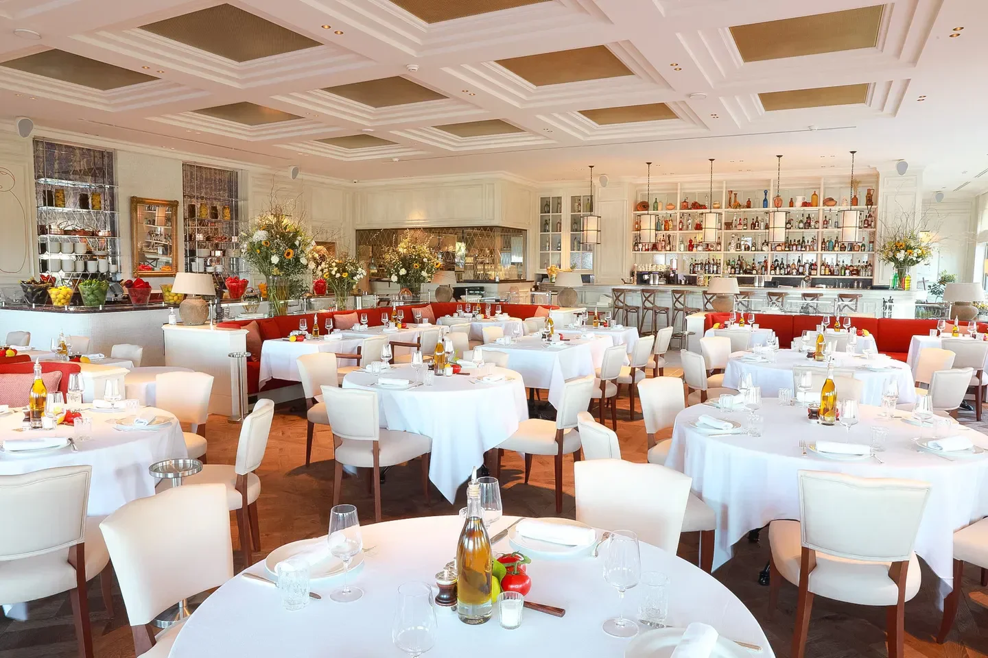 Elegant dining room interior at La Petite Maison in Cannes, France with table settings.