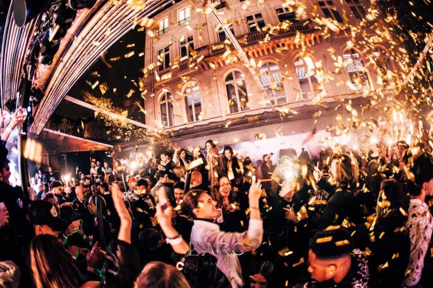 Energetic crowd celebrating at L'ARC nightclub in Cannes with confetti and excitement.