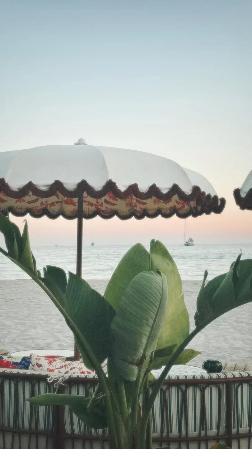 Lucia restaurant in Cannes beach with parasols and sea view at sunset.