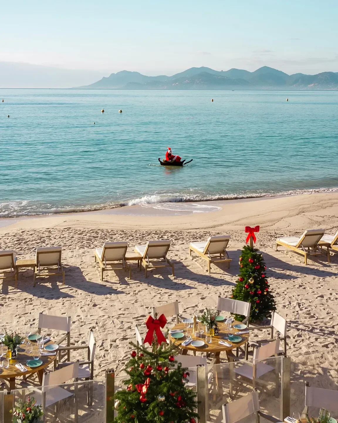 Miramar Plage in Cannes, Santa on a boat in front of Christmas decorated beach restaurant.