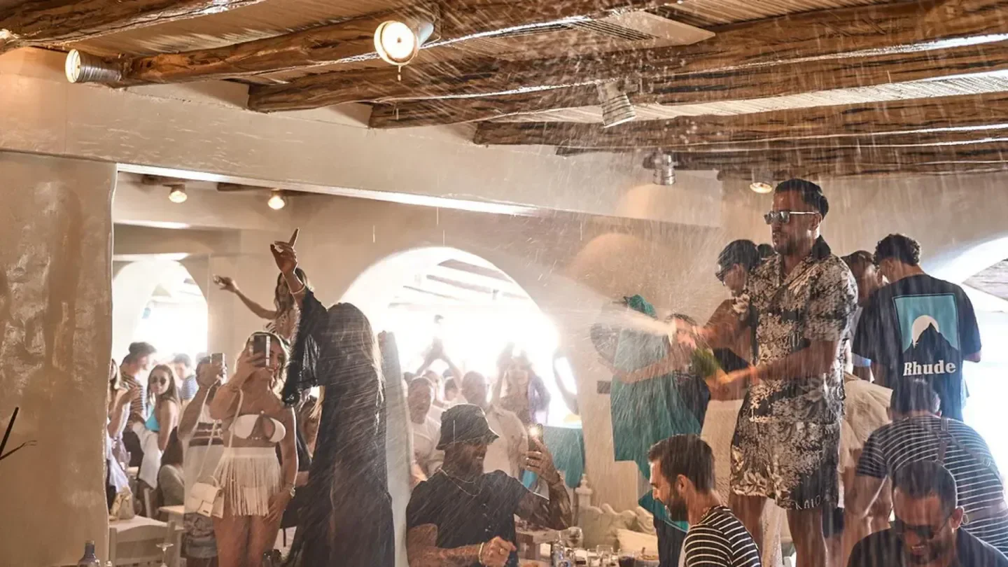 Celebratory champagne spray at Nammos Beach Club in Cannes with a lively crowd.
