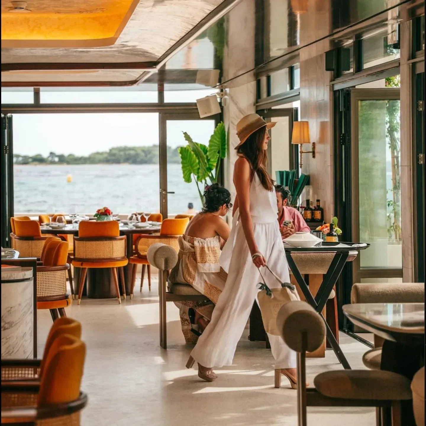 Stylish interior of Palm Beach restaurant in Cannes, featuring sea views and elegant diners.